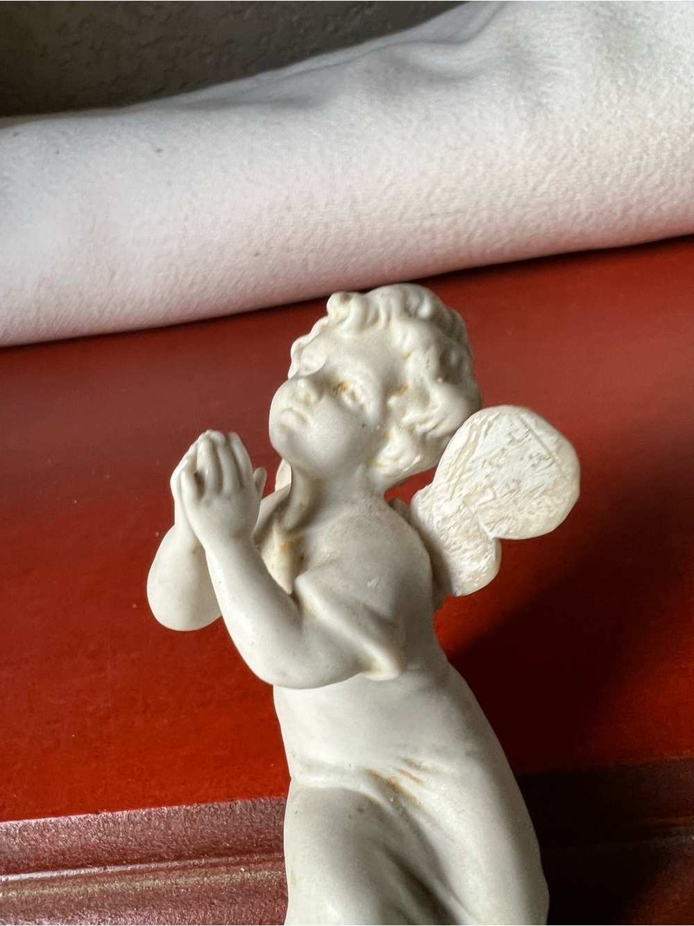 Vintage white porcelain or bisque ceramic figurine a resting cherub or angel,